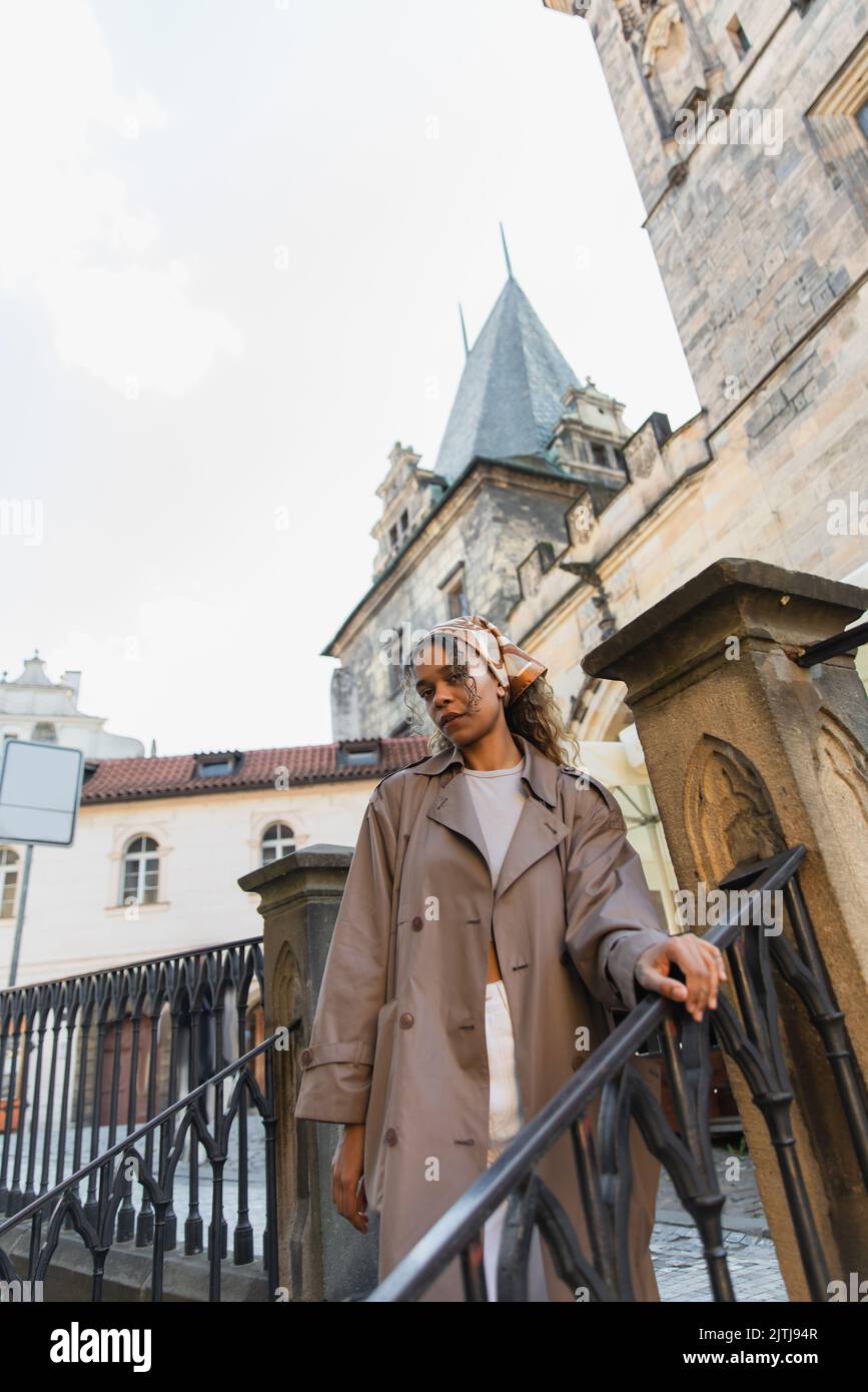 low angle view of stylish african american woman in trench coat near ...