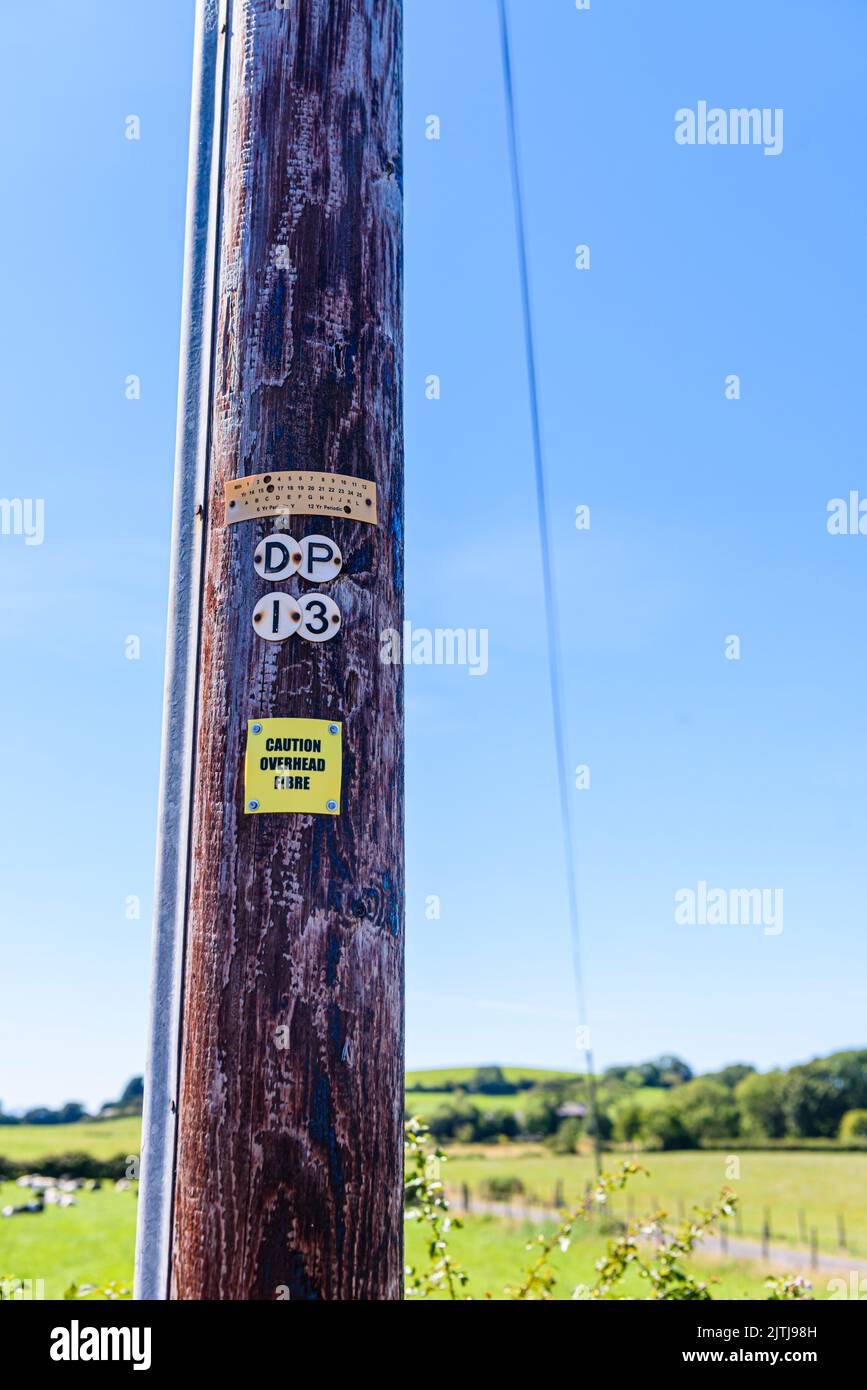 Sign on a wooden telephone pole warning people that the pole is carrying fibre optic cable. Stock Photo