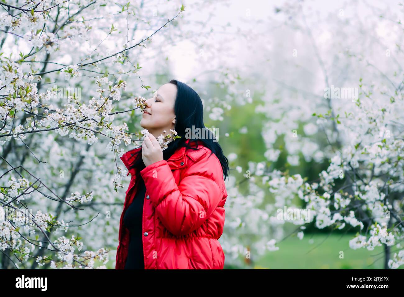 Beautiful happy young woman walks in a flowering spring garden with ...