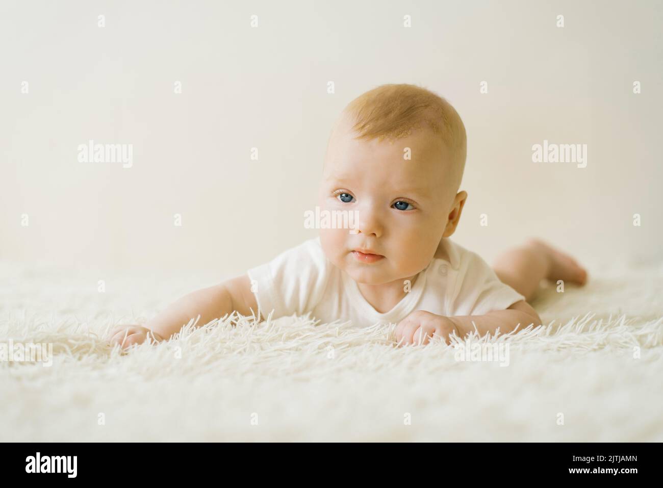 A fivemonthold baby is lying on his stomach on the bed. The concept