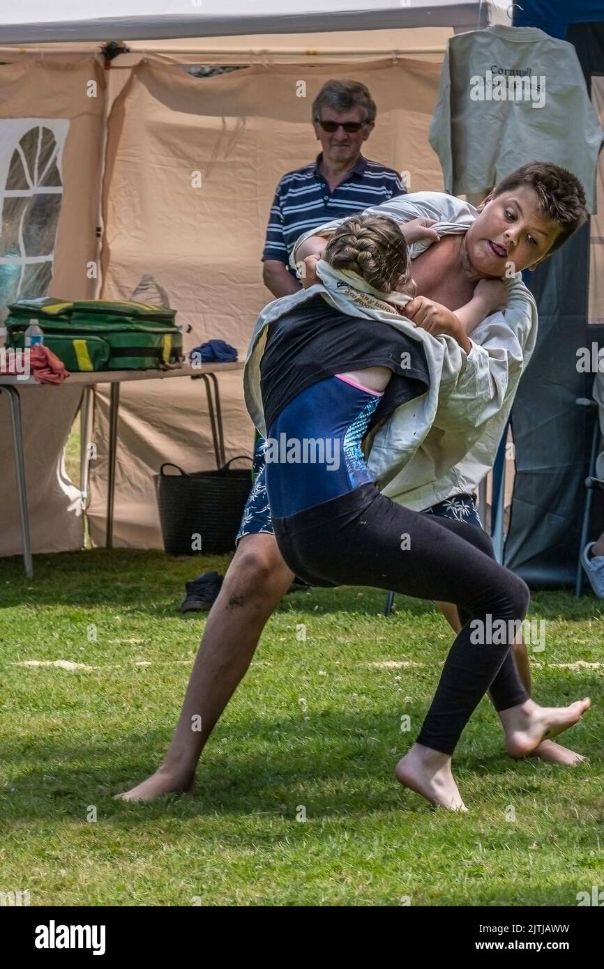 A young girl competing against a bigger boy in the Grand Cornish Wrestling Tournament on the picturesque village green of St Mawgan in Pydar in Cornwa Stock Photo