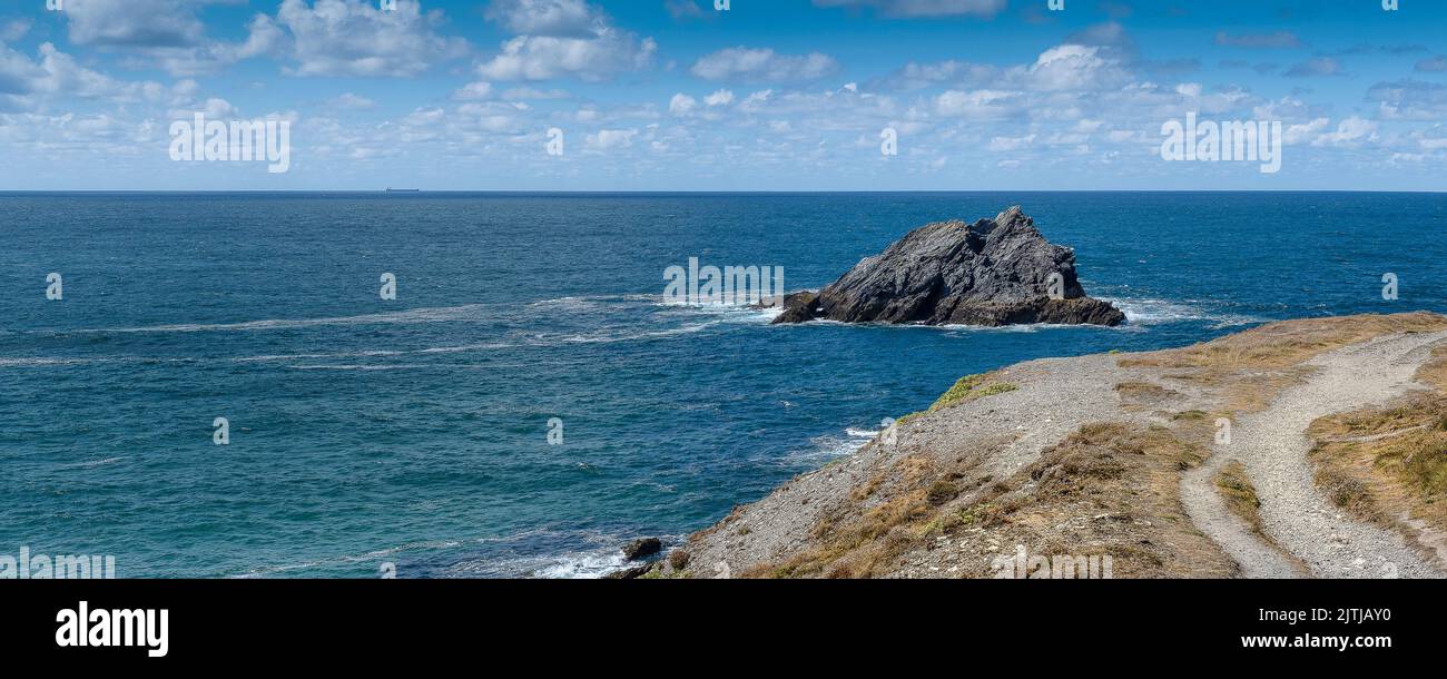 A panoramic image of the rocky island The Goose off the rugged rocks on the coast of Pentire Point East in Newquay in Cornwall in the UK. Stock Photo