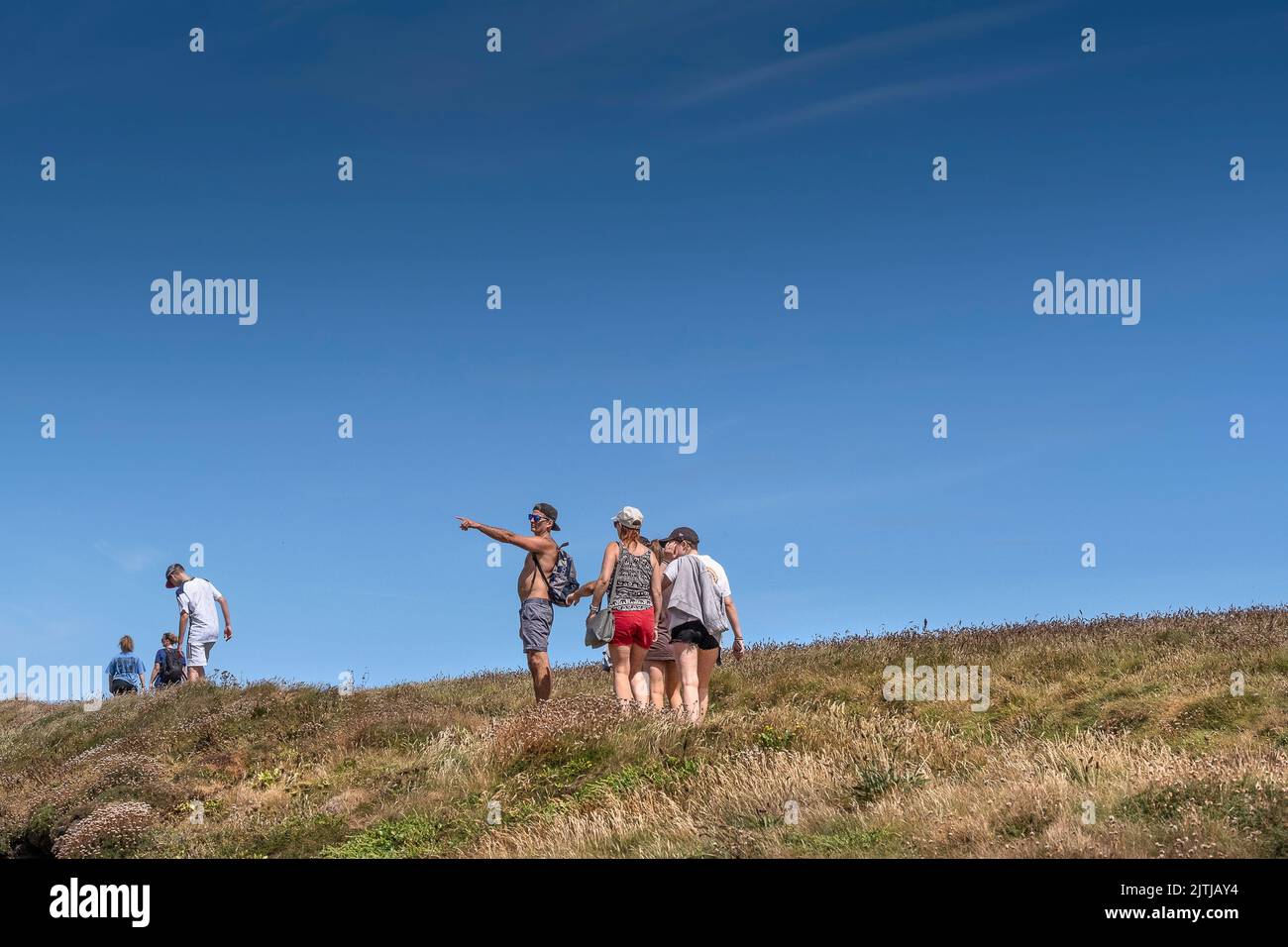 Holidaymakers enjoying a walk along a coast path in Newquay in Cornwall in the UK. Stock Photo