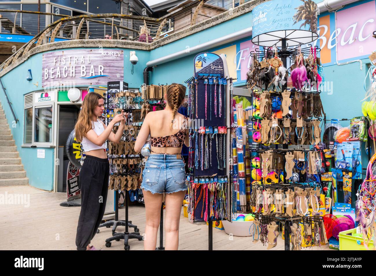 Two young female teenagers looking at jewellery outside a shop at Fistral in Newquay in Cornwall in the UK. Stock Photo