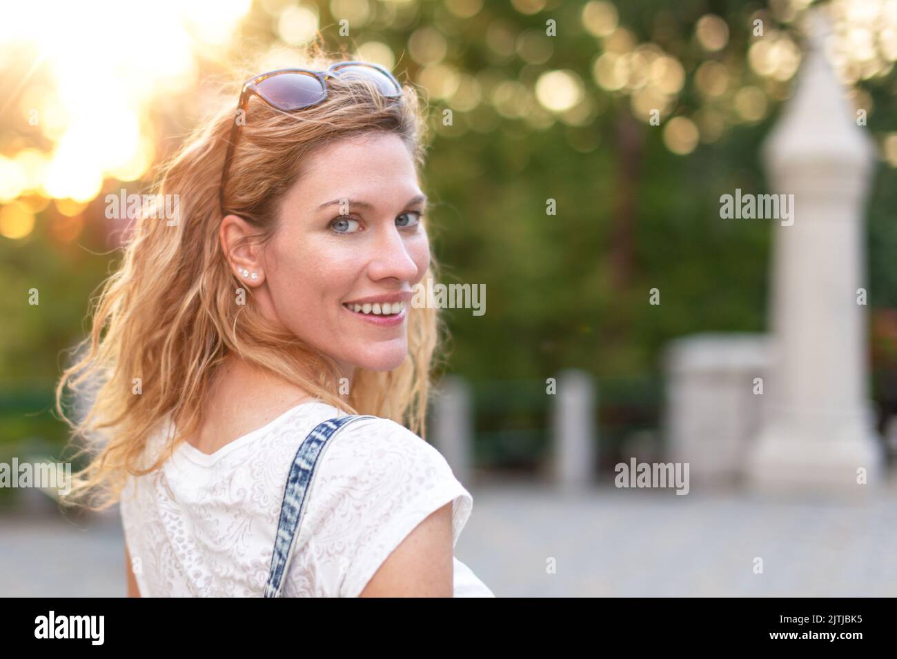 Flirty beautiful natural redhead Caucasian 30s woman looking back in park in sunset. Female attraction. Love at first sight Stock Photo