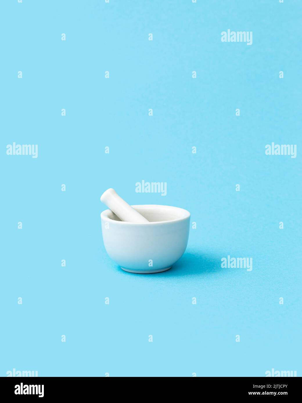 White pharmacy mortar and pestle on the blue background. Visual concept