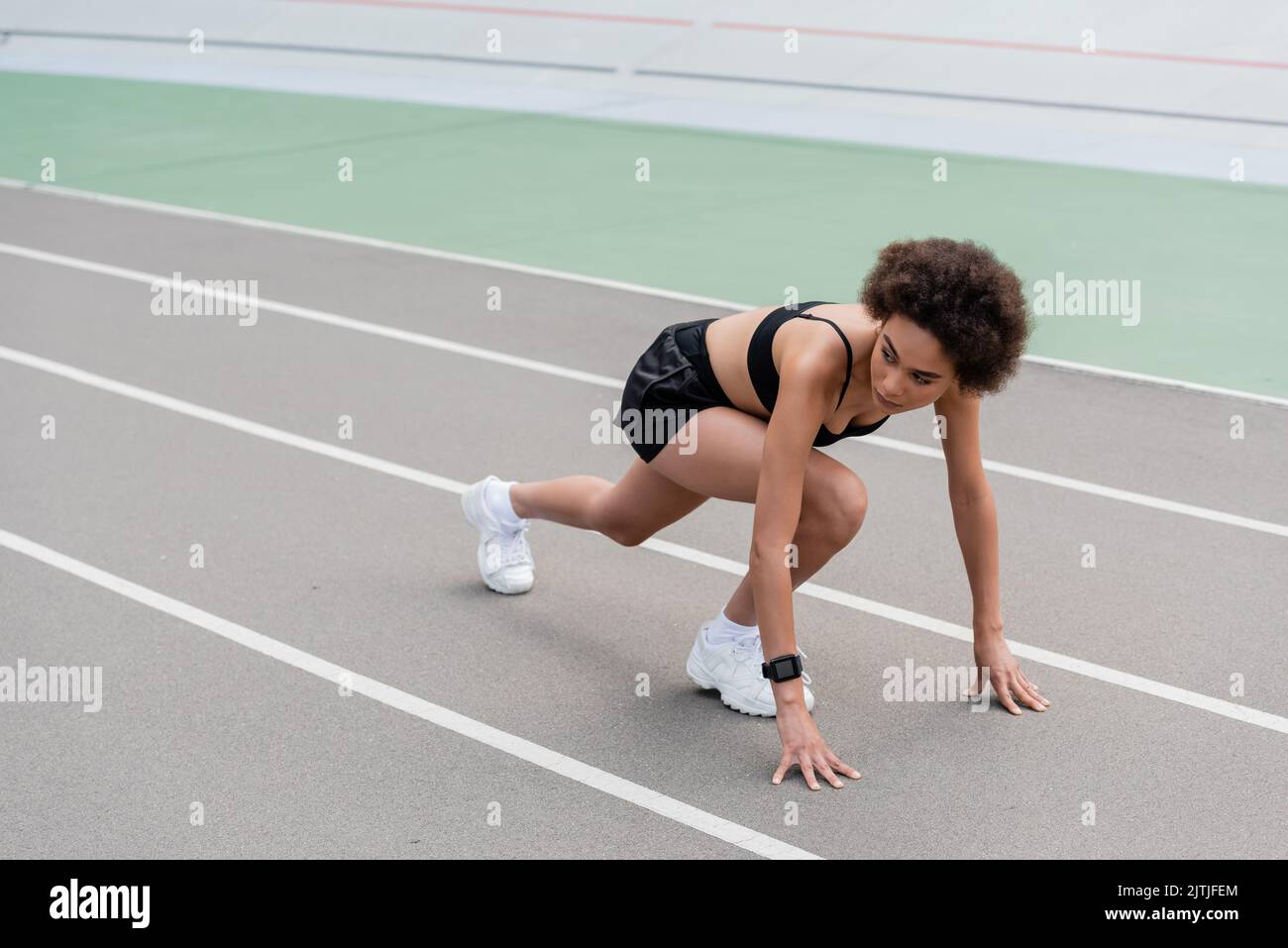 slim african american runner looking away while standing in low start ...