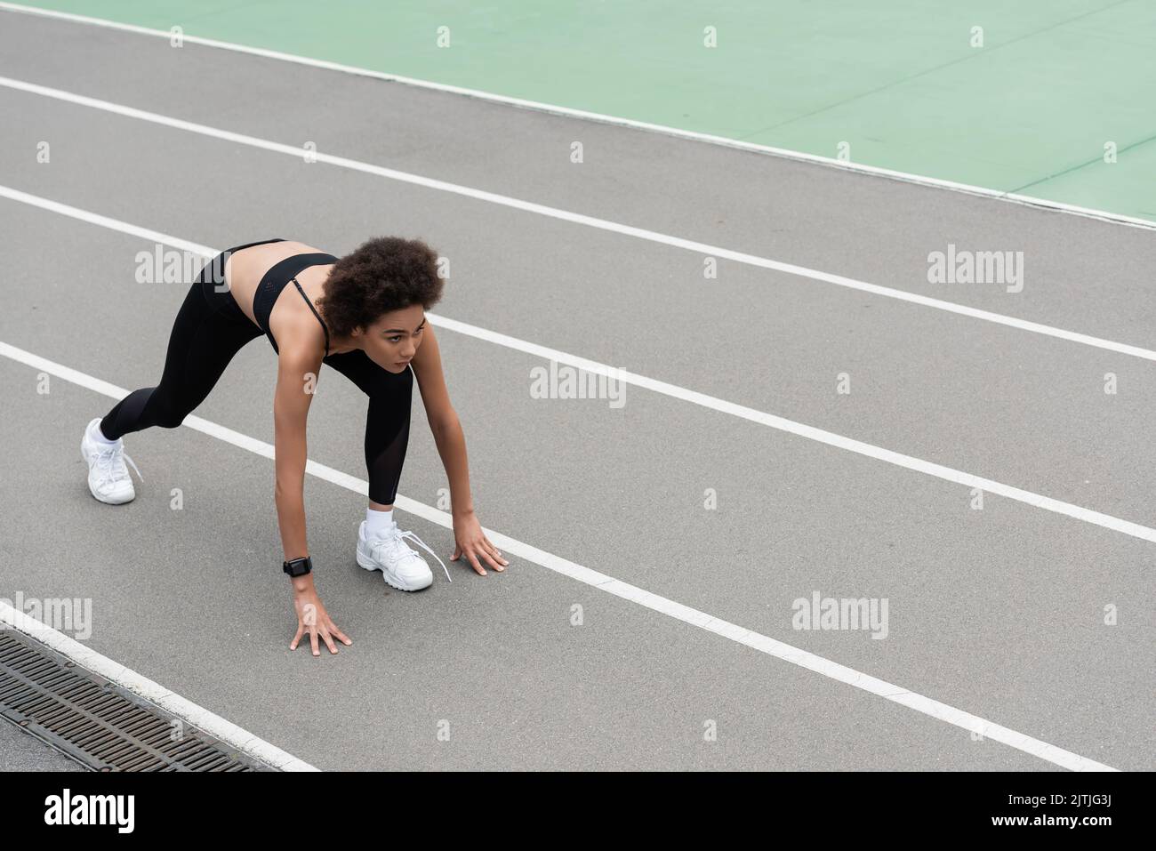 high angle view of african american runner standing in low start pose on track Stock Photo