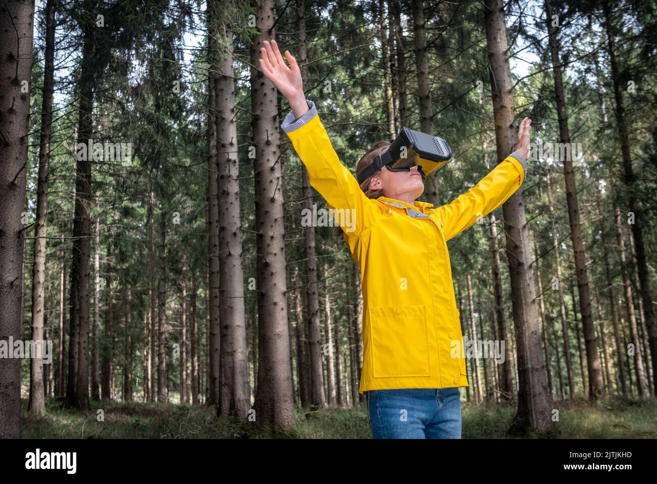 Woman wearing virtual reality headset standing in a forest Stock Photo