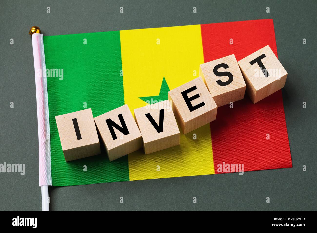 Wooden cubes with text and flag on a colored background, the concept of investment in Senegal Stock Photo