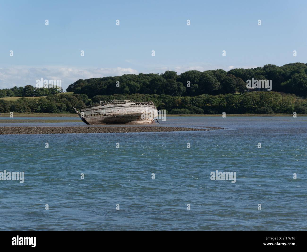 Abandoned wooden fishing boat on a sandbank in Traeth Dulas estuary Isle of Anglesey North Wales UK on a lovely August day with blue sky Stock Photo