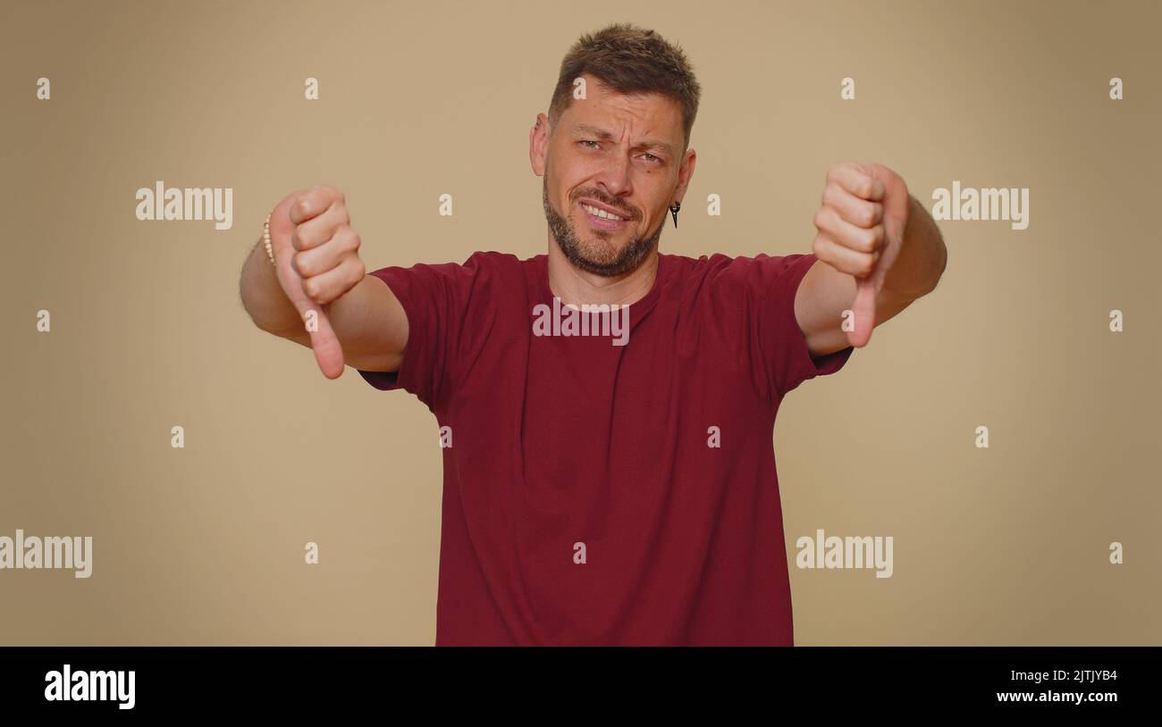 Upset bearded handsome young man showing thumbs down sign gesture ...