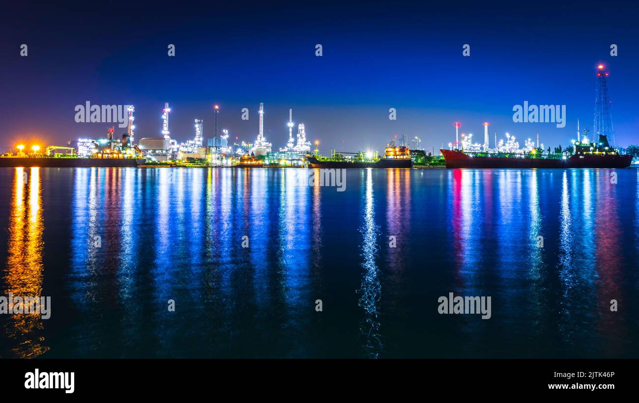 Cityscape at night with a lighting reflection in a river. Oil refinery ...