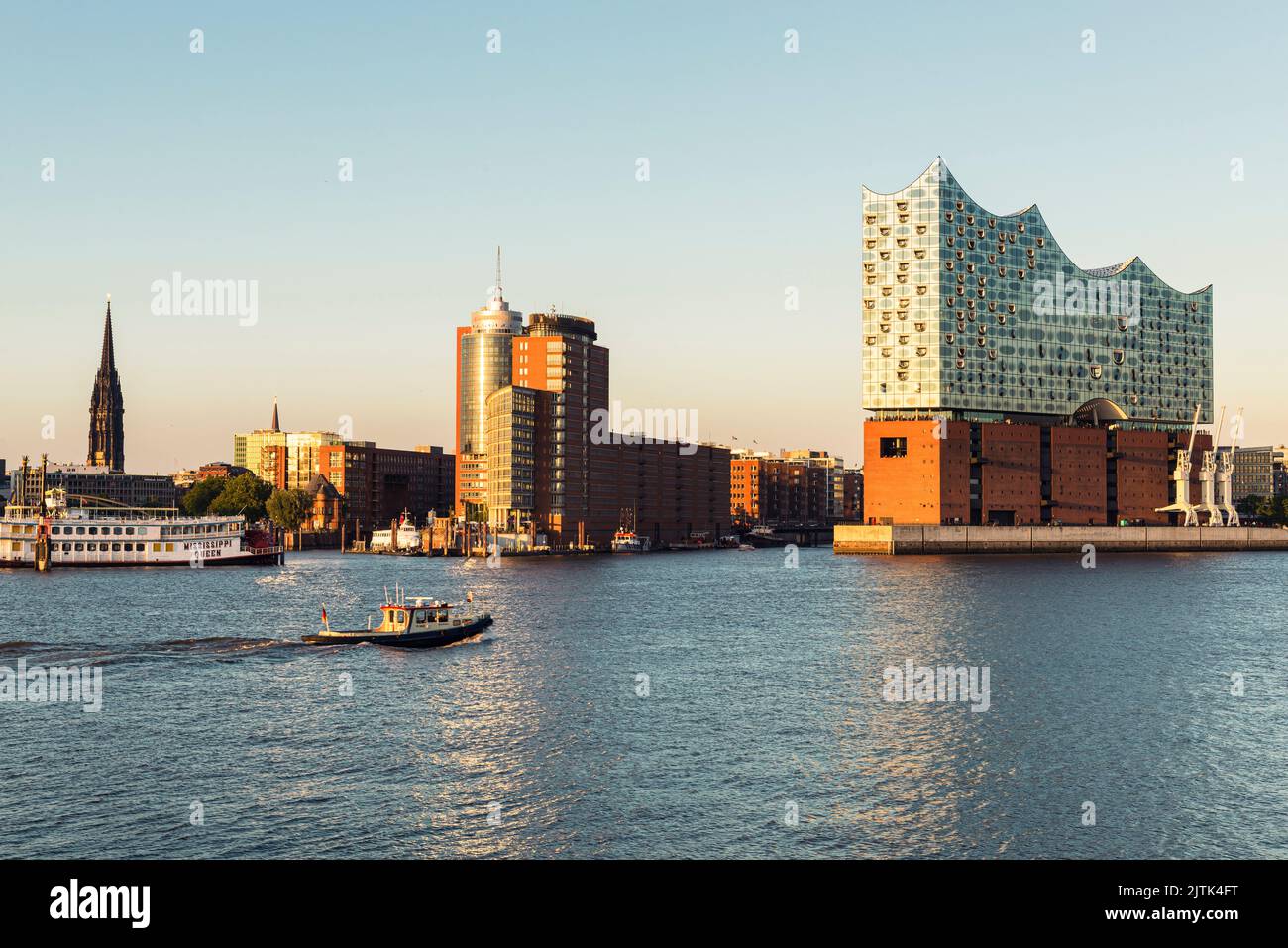 St.Nikolai, the Übersee Bridge, the warehouse district, the Elbphilharmonie Concert Hall and HafenCity in the harbour of Hamburg shortly before sunset Stock Photo