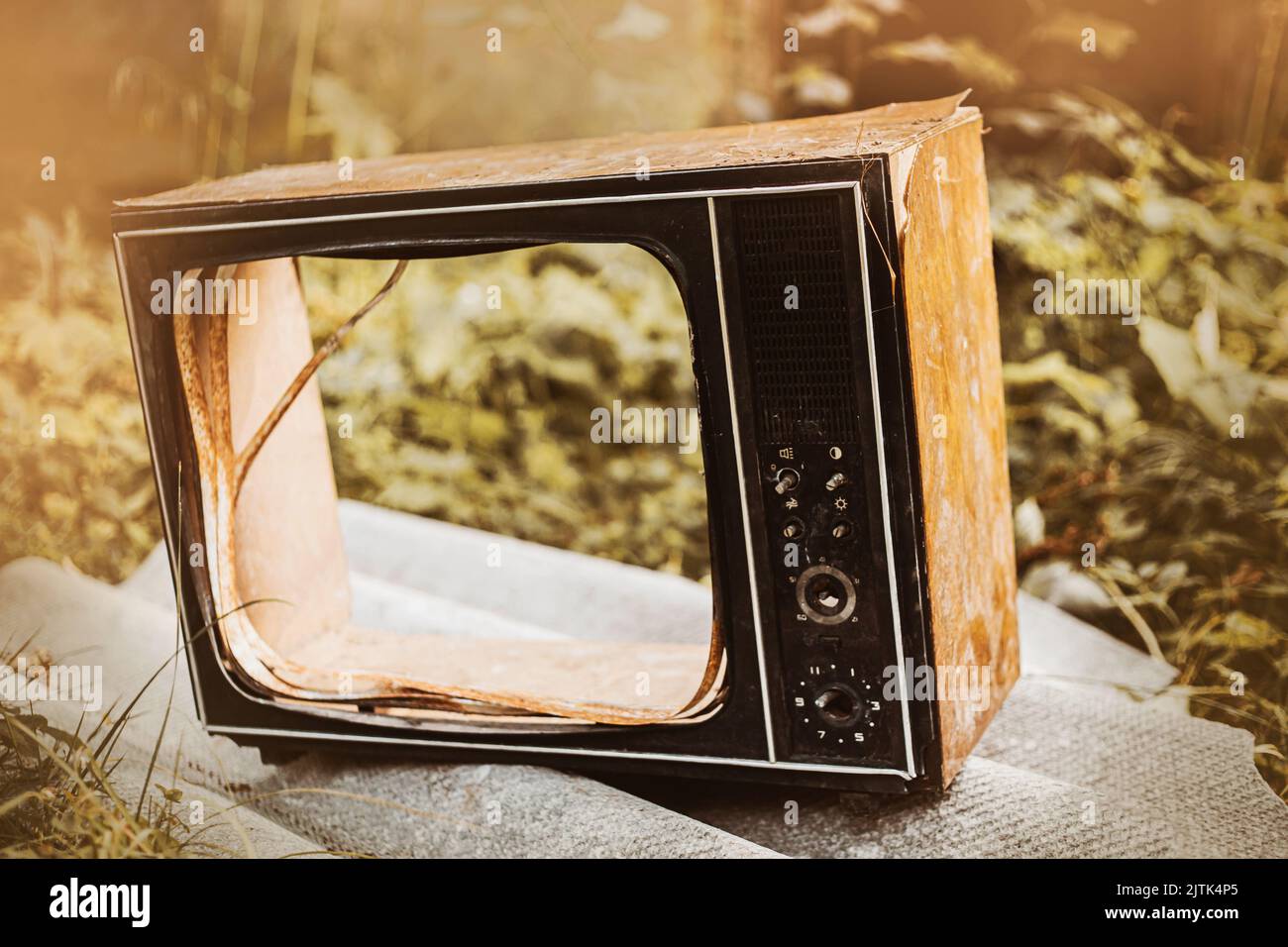A broken old retro TV with a broken screen is lying in the trash. The