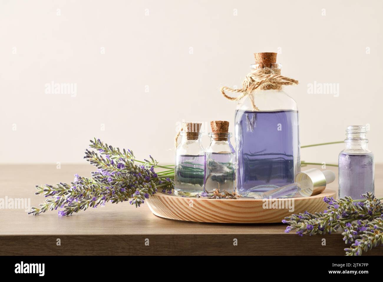 Natural perfume with lavender essence background in bottles and bouquets of spikes around on wooden table and white isolated background. Front view. H Stock Photo