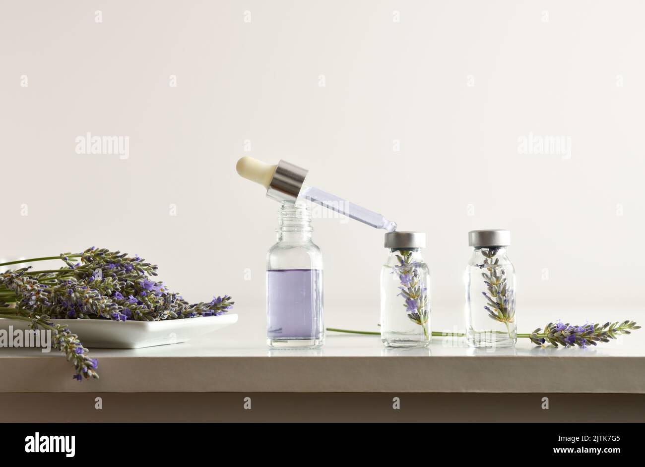 Vials with lavender essence preparation on a white laboratory bench and white isolated background. Front view. Horizontal composition. Stock Photo