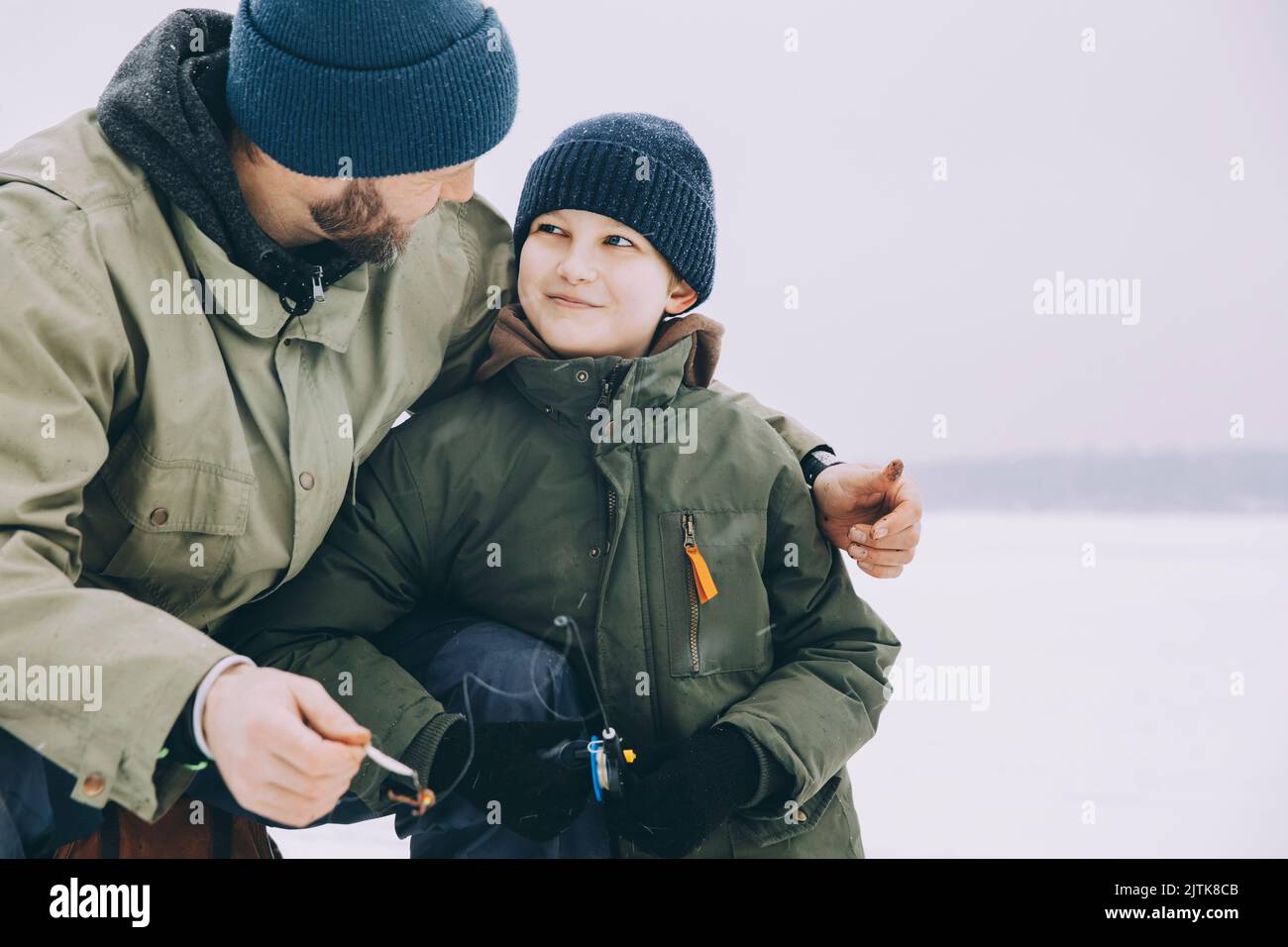 Smiling boy in warm clothing looking at father during winter Stock Photo