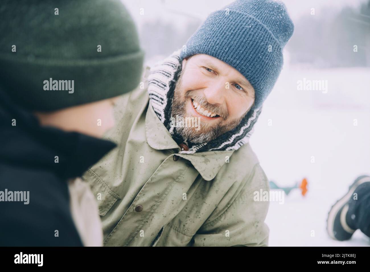 Happy mature man wearing knit hat talking with boy Stock Photo