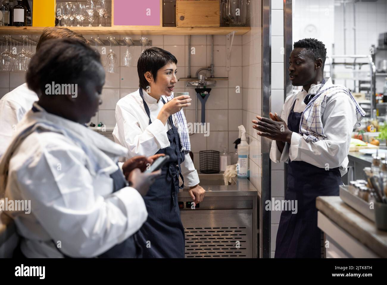 Multiracial chefs talking during break in commercial kitchen Stock ...