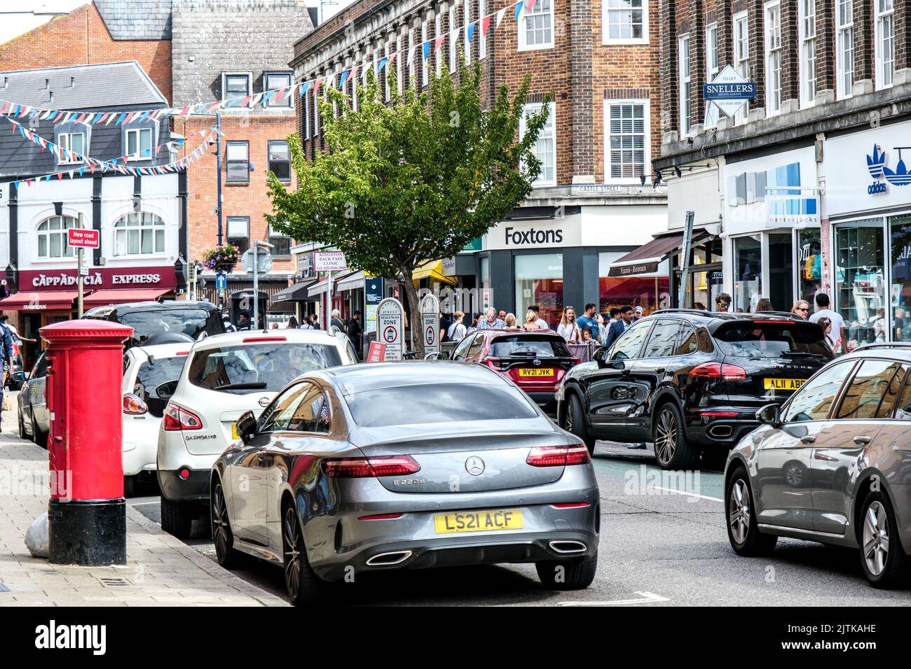 Kingston-Upon-Thames, London, UK, August 29 2022, Cars Parked Along Main Street Shopping Area With Red Post Box With Shoppers Or Consumers Stock Photo