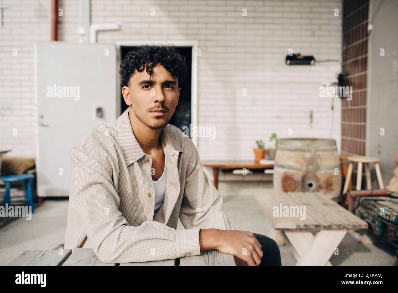 Portrait of young man sitting at table in front of wall Stock Photo