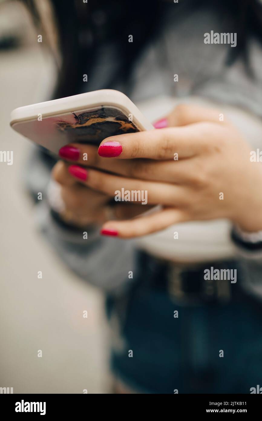 Midsection of woman text messaging through smart phone Stock Photo
