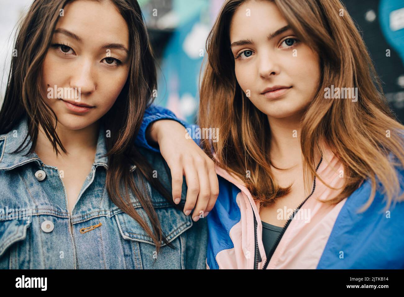 Portrait of confident young woman with hand on shoulder of female friend Stock Photo
