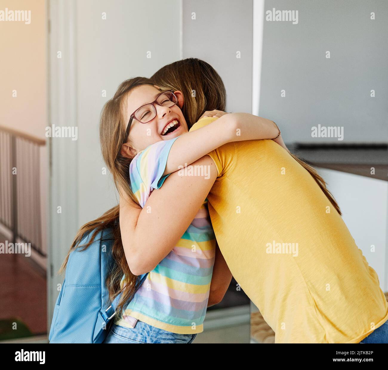 child mother daughter backpack house education school family student welcome hug together love woman elementary home girl woman Stock Photo