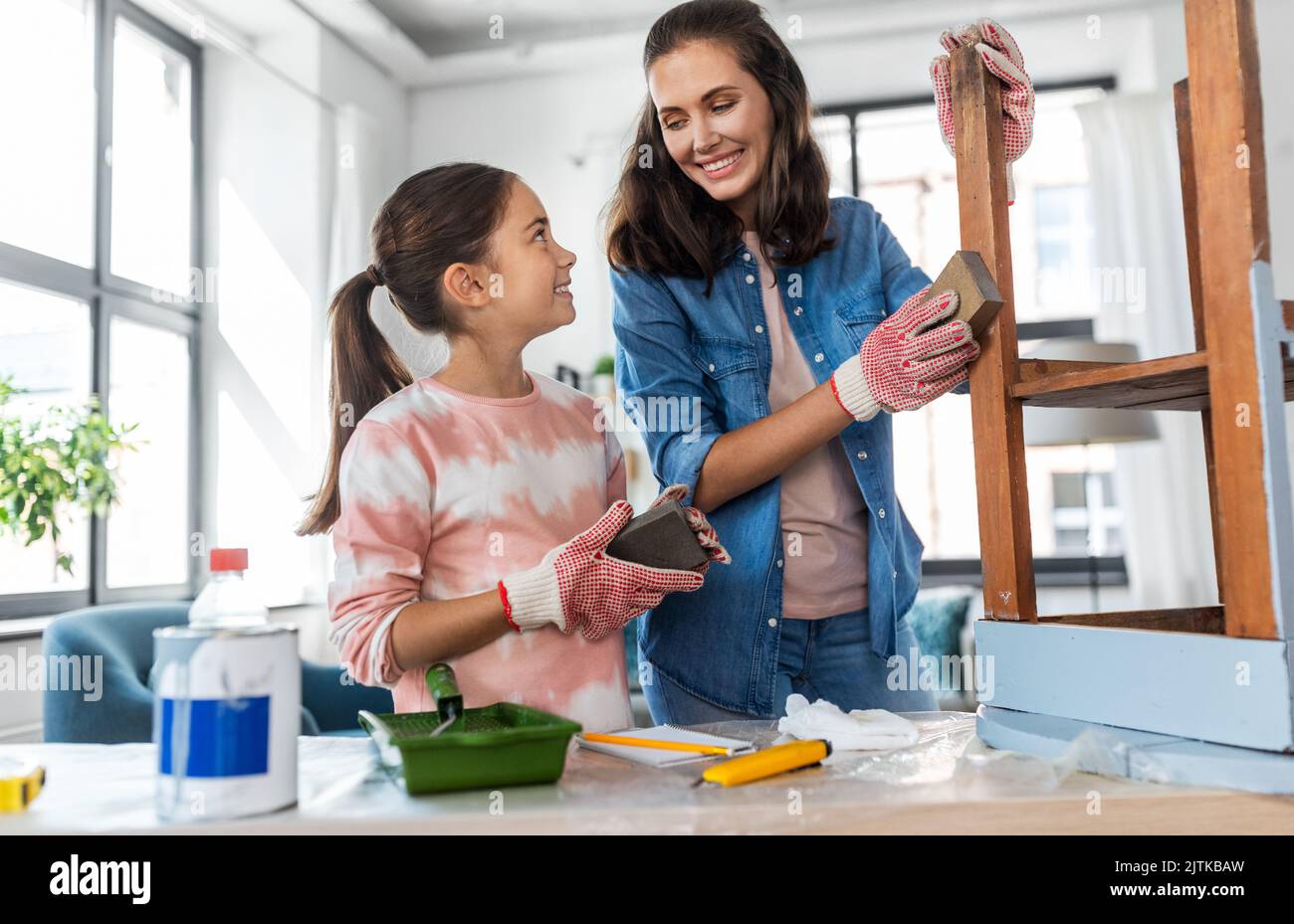mother and daughter sanding old table with sponge Stock Photo