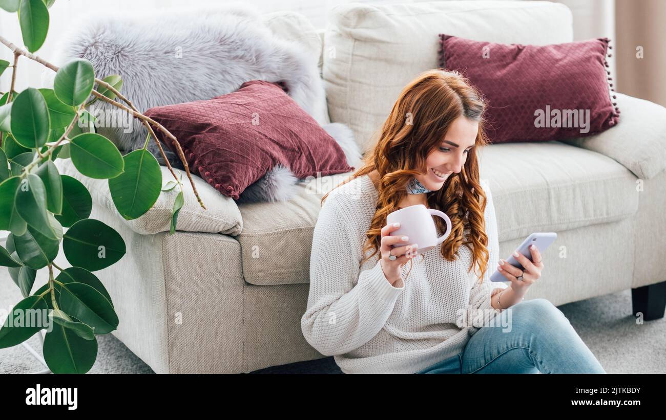 woman leisure cozy home cup browsing smartphone Stock Photo