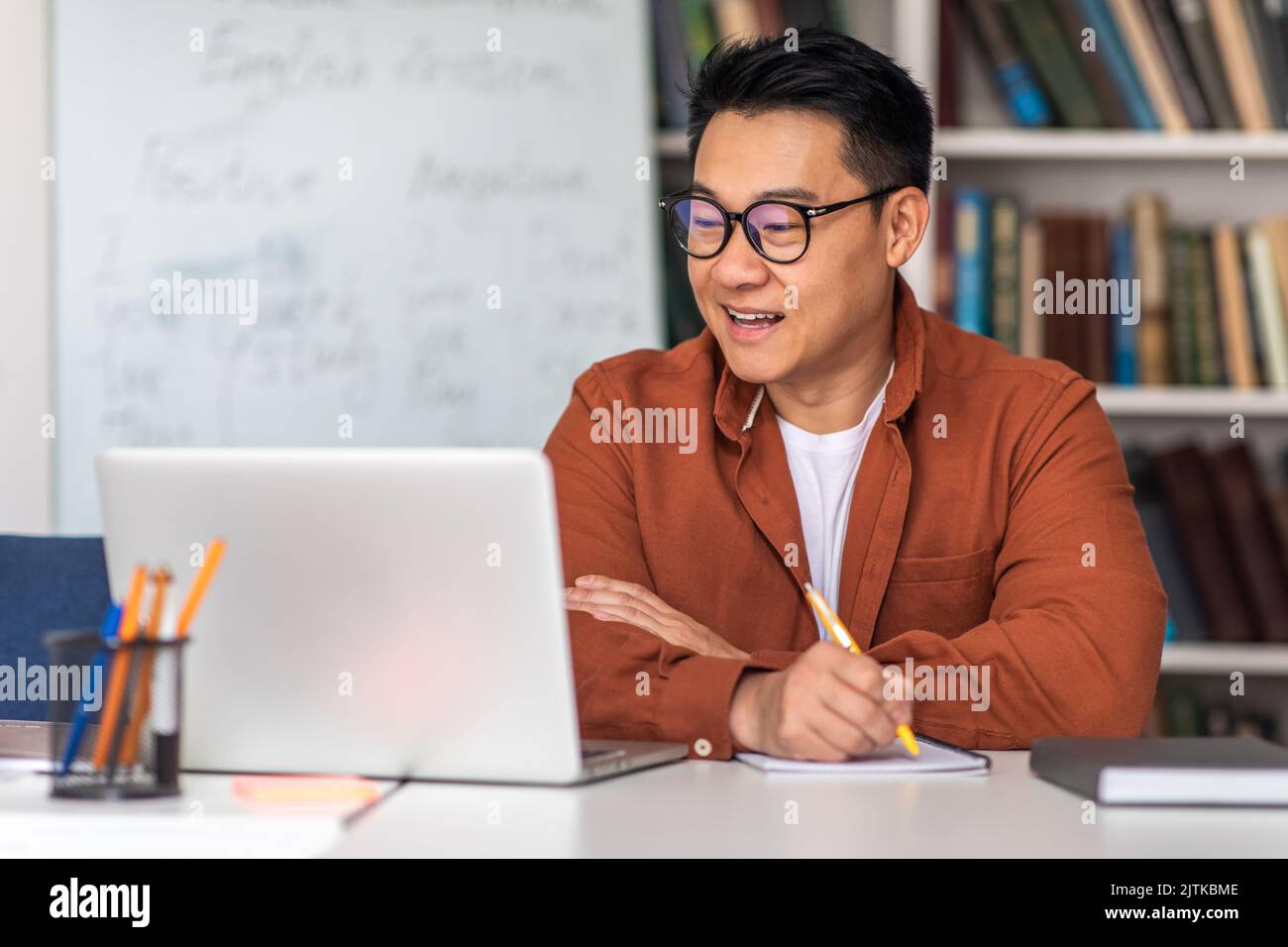 Asian Tutor Having Online Class Via Laptop Taking Notes Indoor Stock ...