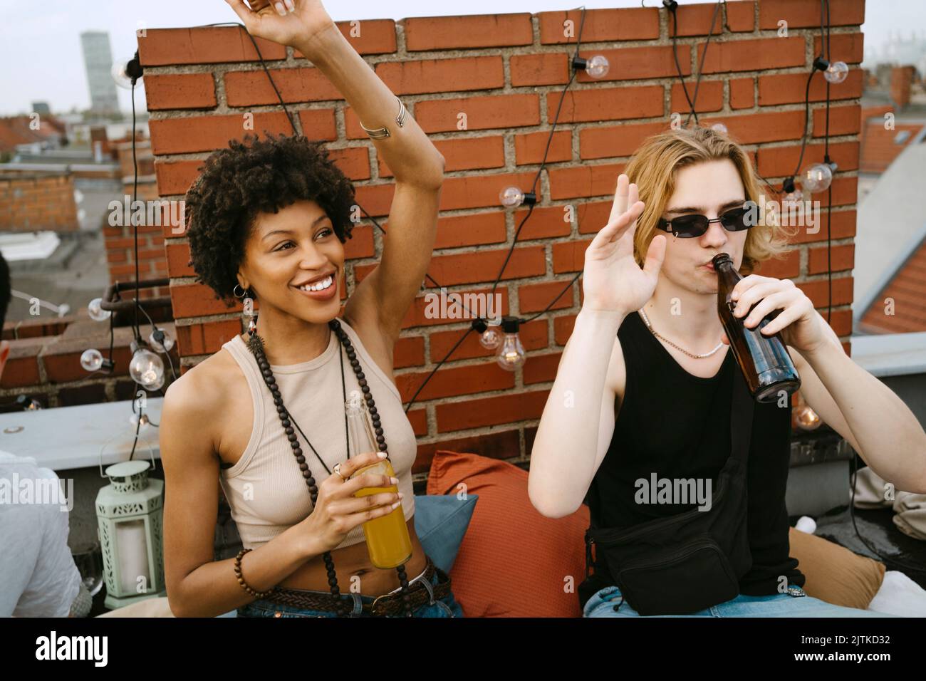 Happy woman and man with hands raised drinking beer on rooftop Stock ...