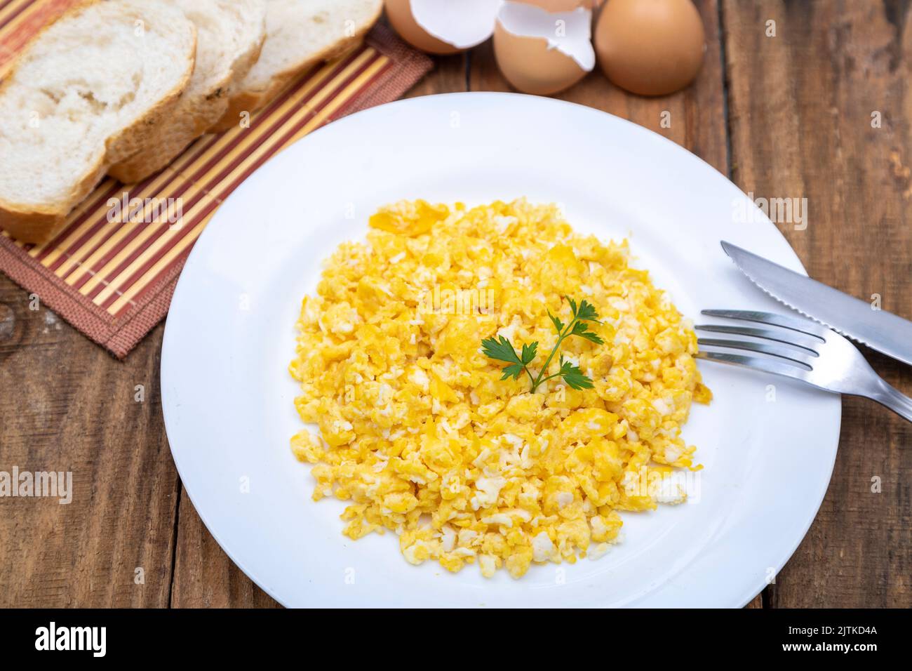 fresh scrambled eggs on white plate on breakfast table Stock Photo