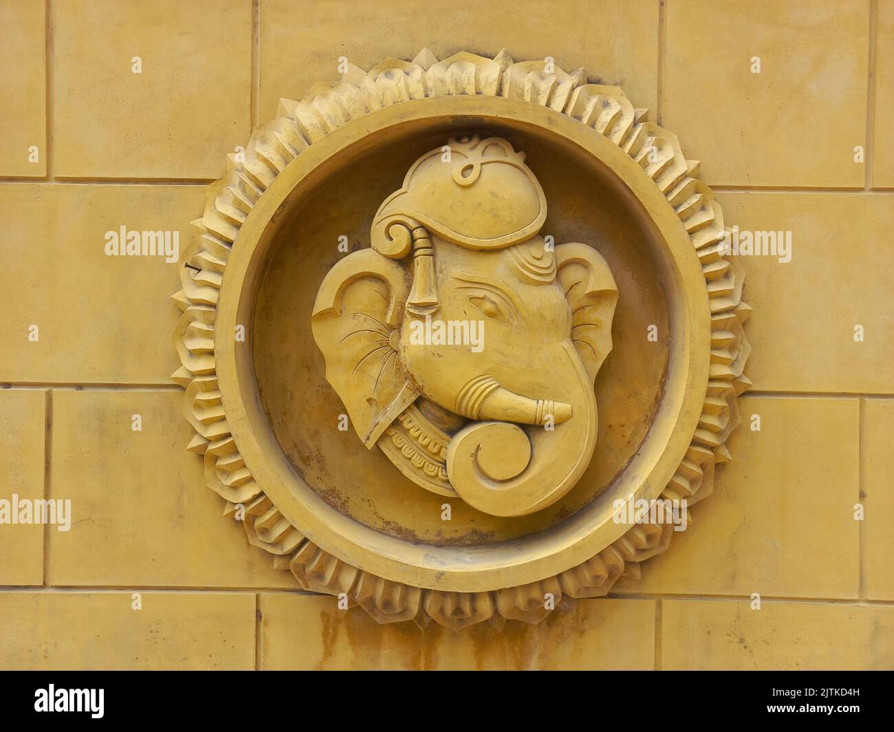 A stone sculpture of the head of Lord Ganesha hanging on the wall Stock Photo