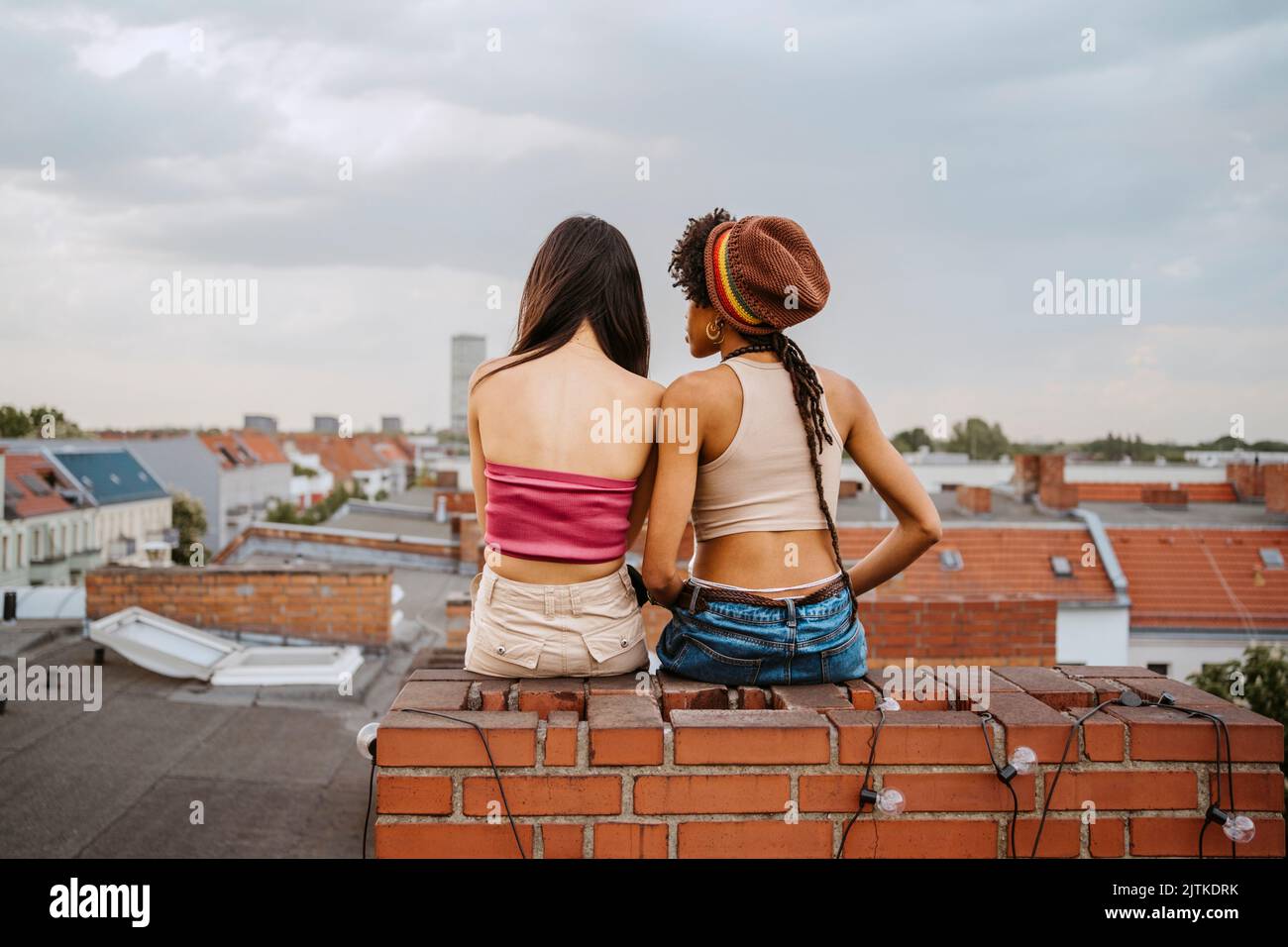 Rear view of young women sitting together on rooftop Stock Photo