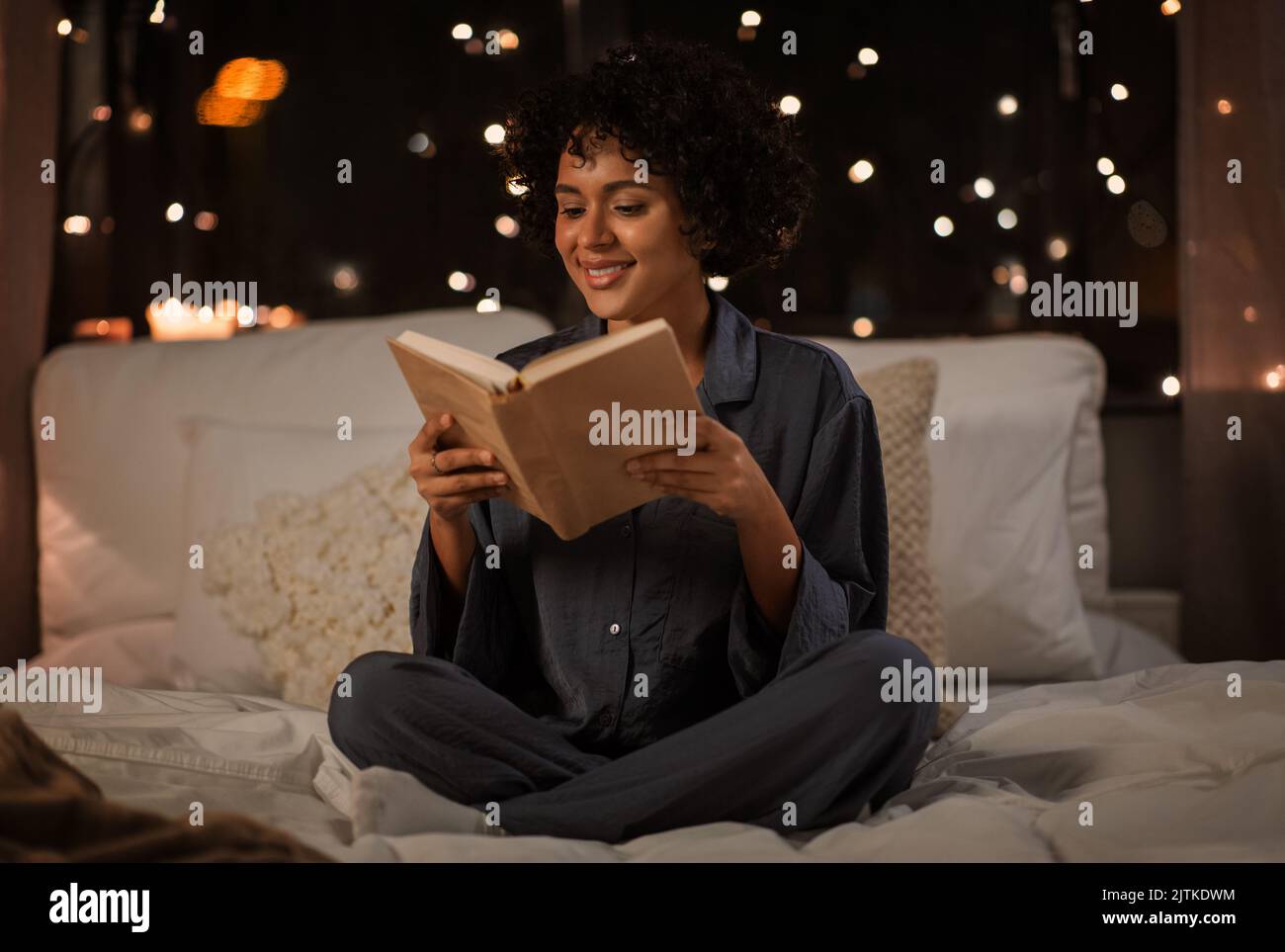 happy woman reading book sitting in bed at night Stock Photo - Alamy