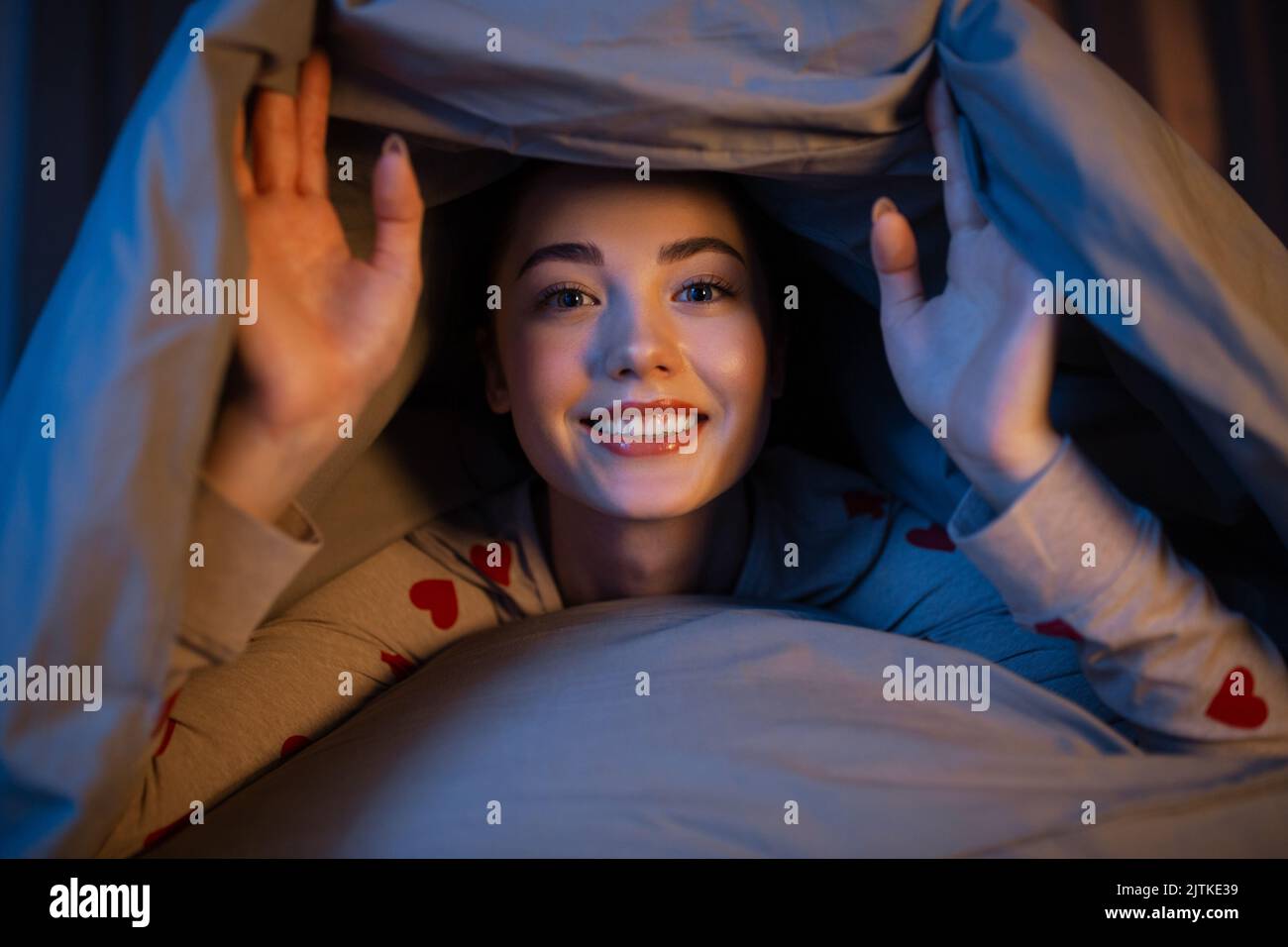 happy teenage girl lying under blanket in bed Stock Photo Alamy