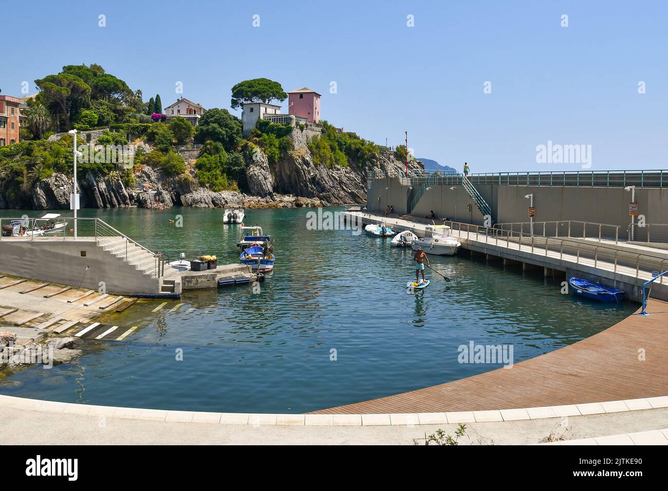 View of the small port of the old fishing village with a man sup paddling in summer, Nervi, Genoa, Liguria, Italy Stock Photo