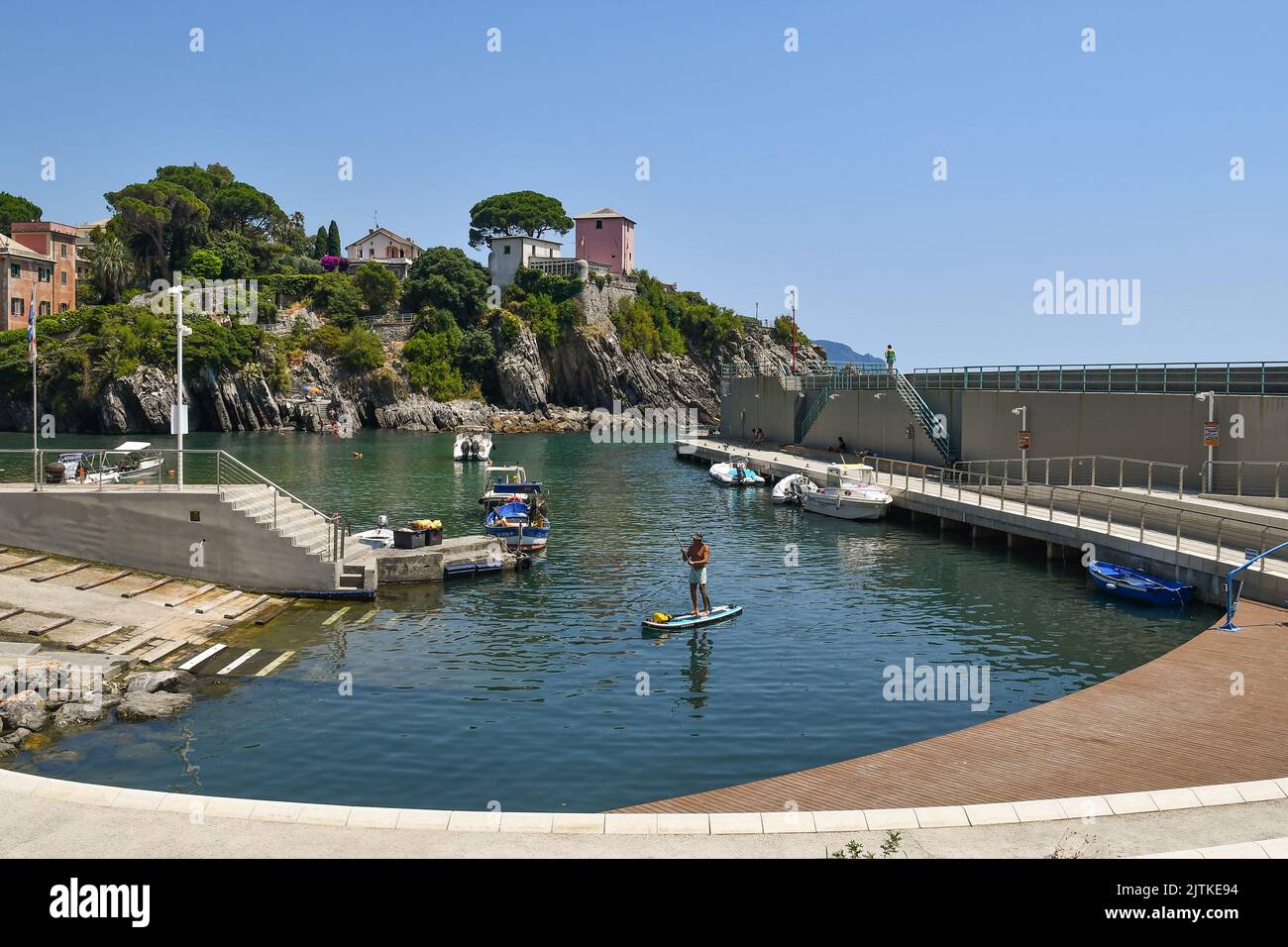 View of the small port of the old fishing village with a man sup paddling in summer, Nervi, Genoa, Liguria, Italy Stock Photo