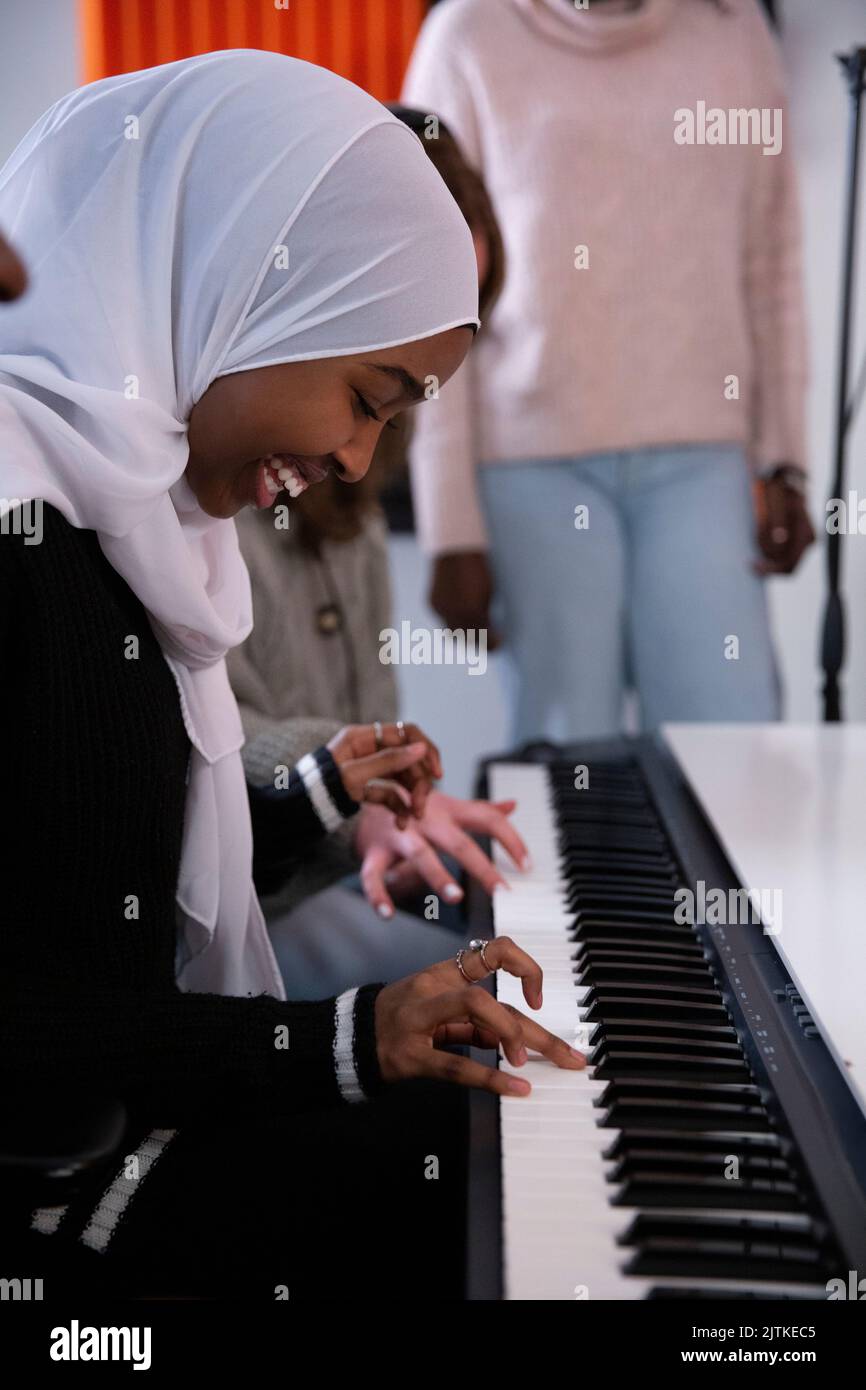 Girl in hijab playing piano in recording studio Stock Photo