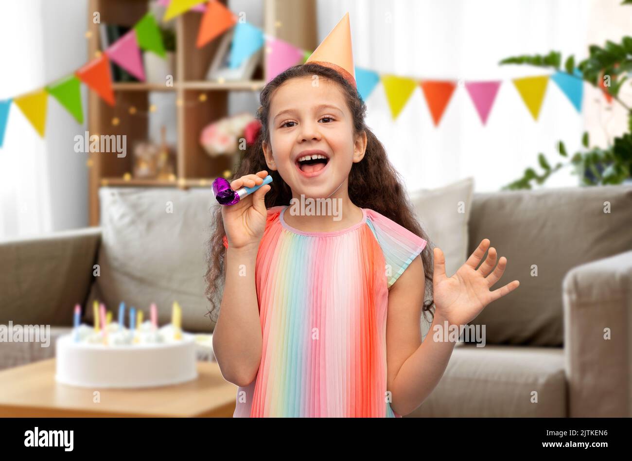 smiling girl in birthday party hat with blower Stock Photo - Alamy