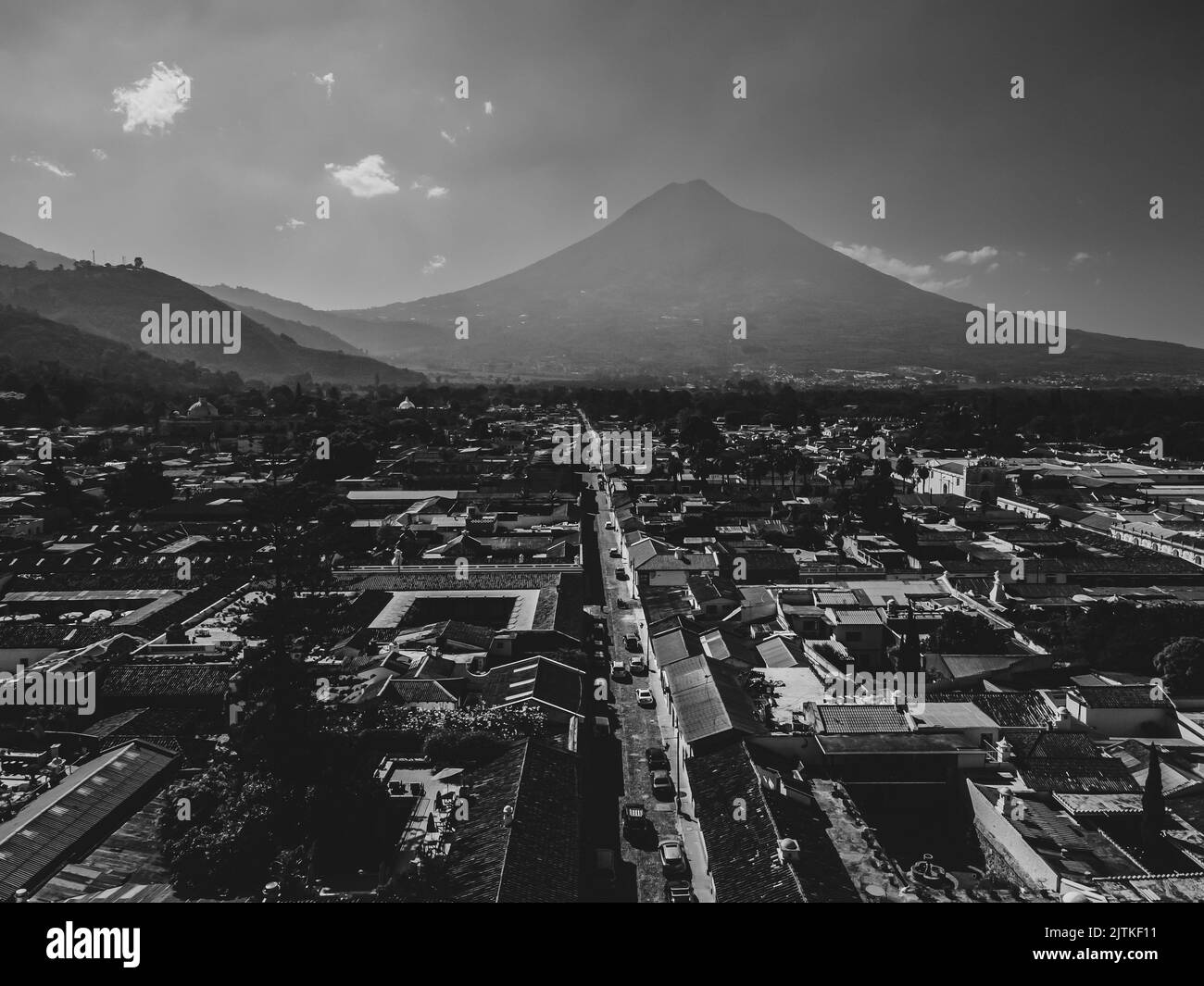 Beautiful aerial cinematic footage of the Antigua City in Guatemala, Its yellow church, the Santa Catalina Arch and the Acatenango Volcano Stock Photo