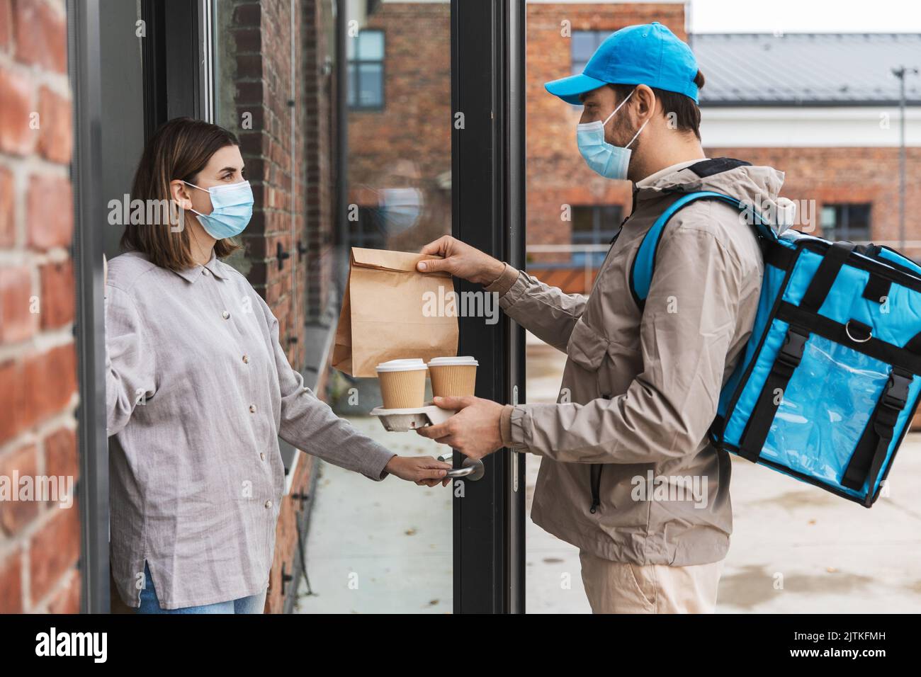 food delivery man in mask giving order to customer Stock Photo - Alamy