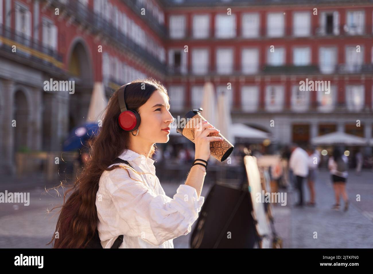 Young female tourist listening to music and walking through the streets of Madrid. Stock Photo