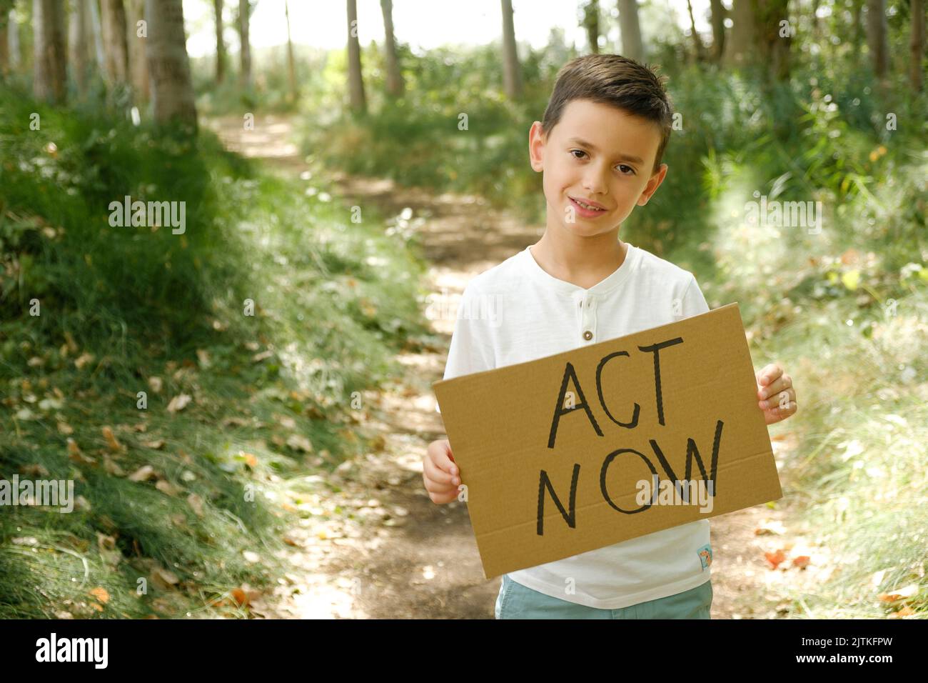 child displays sign with the message 'act now' Stock Photo