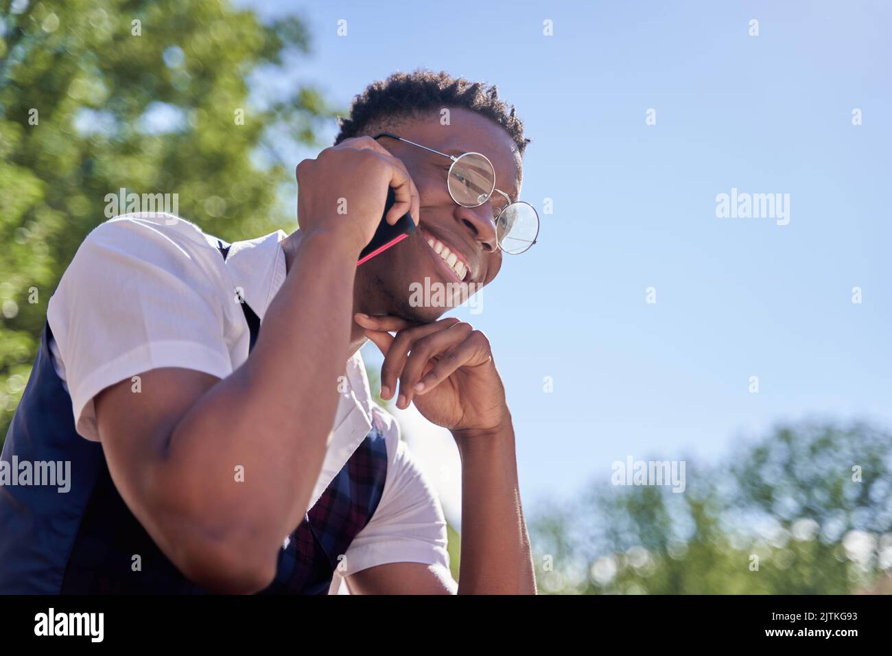 Young african american man laughs while talking on the phone on the street. Stock Photo