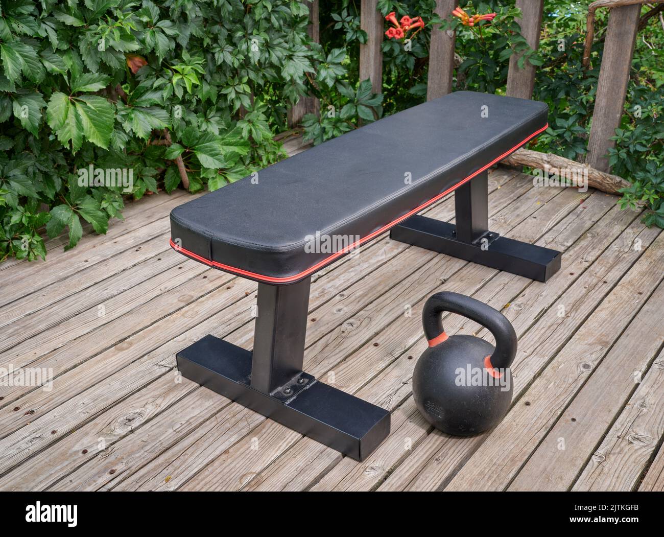 exercise bench and heavy iron kettlebell on wooden backyard deck Stock