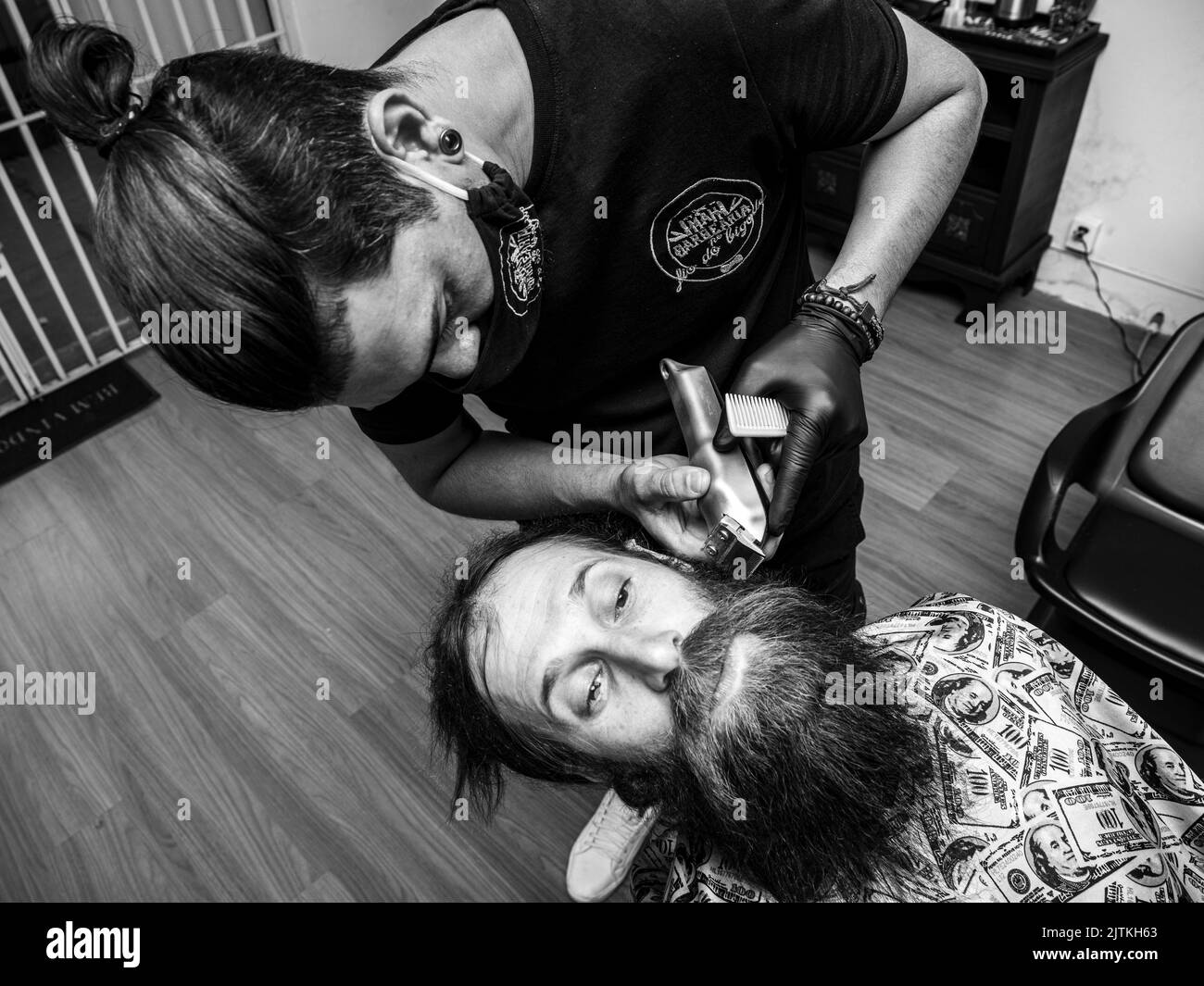 Barber using shaver to cut beard of a man Stock Photo Alamy