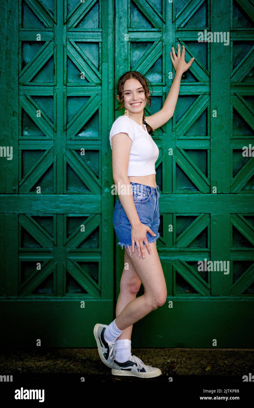 Fun Full Length Portrait of Young Woman in Front of Large Ornate Green Door Stock Photo